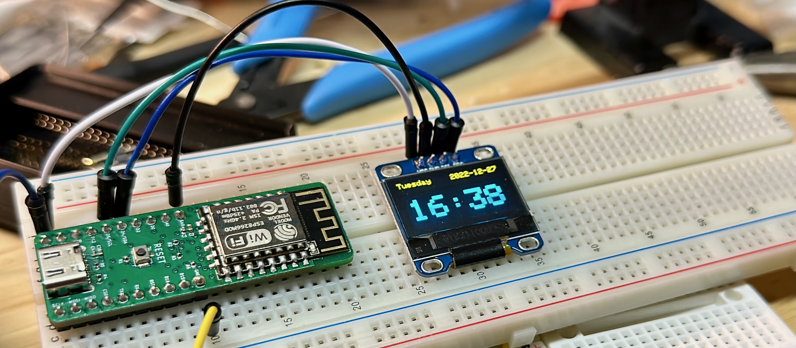 An assembled board running an OLED screen showing the date/time